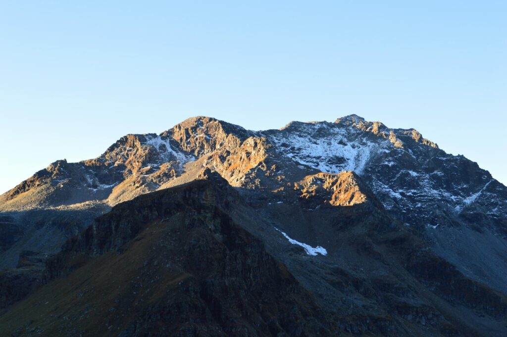 Breathtaking view of a snow-capped mountain range under a clear blue sky at sunset.