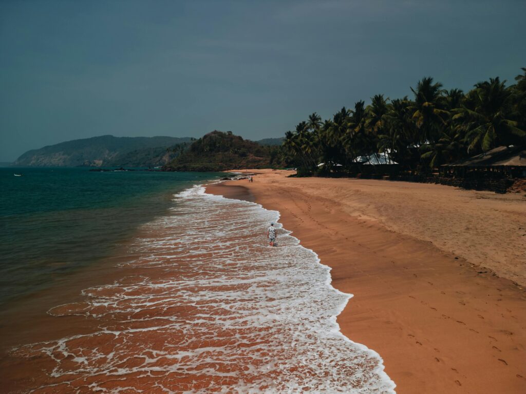 A picturesque aerial view of a serene beach in Goa with golden sands and gentle waves during sunset.